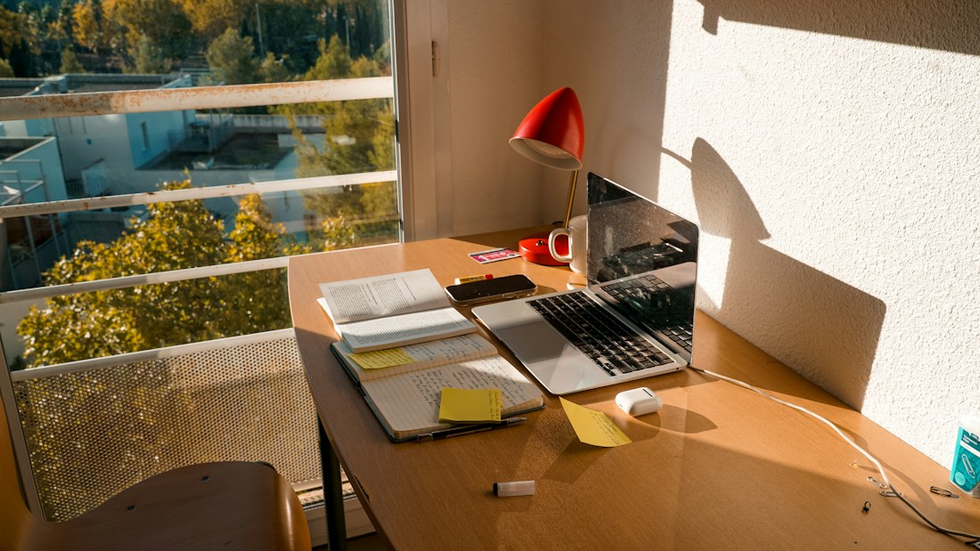 A quiet desk with a laptop and office supplies beside a window